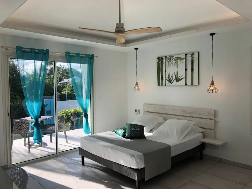 Chambre Orchidée  + ventilateur en bois sur plafond avec baie vitrée et vue sur le jardin tropical 