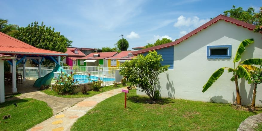 Berceuse créole : gîtes de vacances d'architecture créole et toiture en tôle roule autour d'une piscine.