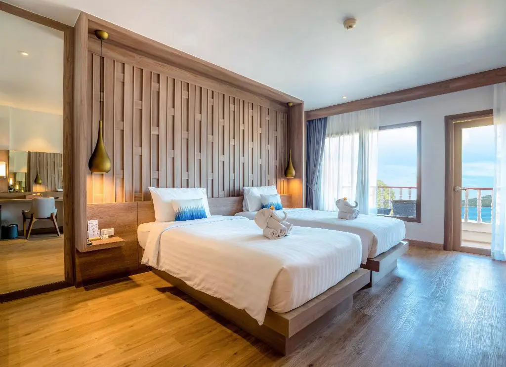 Vaste chambre avec deux lits ,parquet ,  luminaire en cuivre , décoration du mure en bois + superbe vue sur la plage .