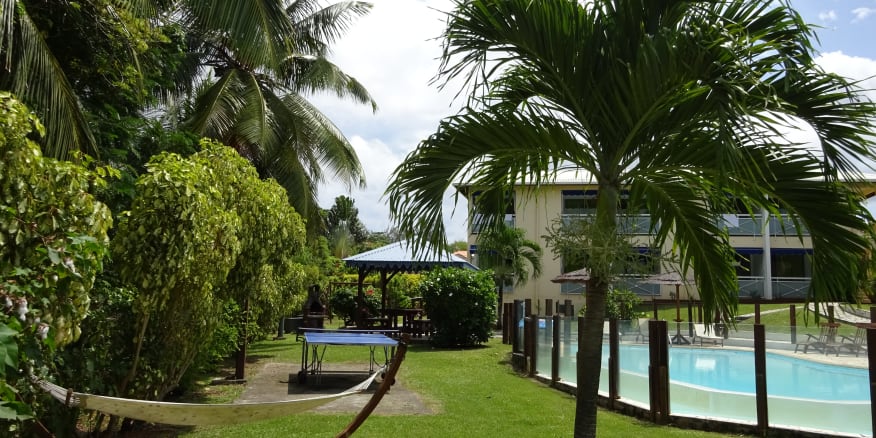 Jardin tropical de la résidence Créoline avec piscine ,carbet et table de ping pong . Résidence cerné de palmiers.