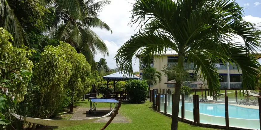 Jardin tropical de la résidence Créoline avec piscine ,carbet et table de ping pong . Résidence cerné de palmiers. 