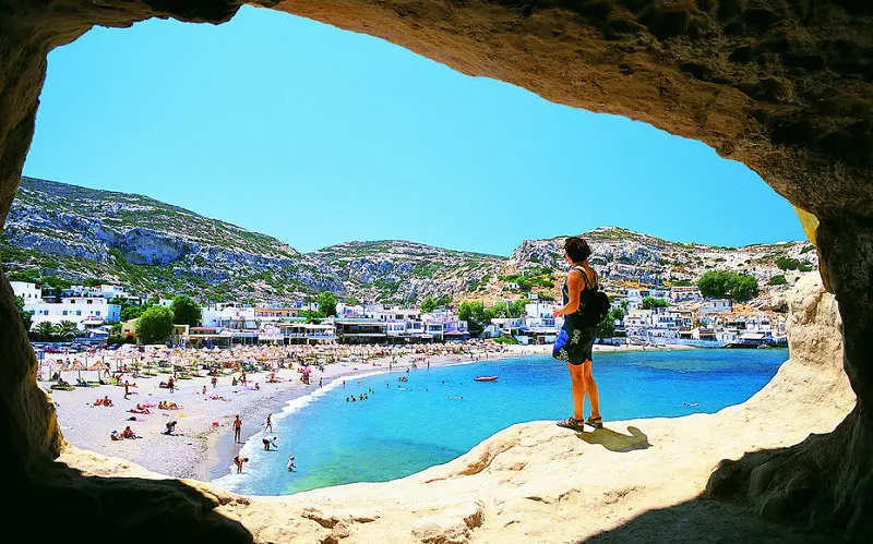 Plage de Crète perçu par une grotte avec une vue magnifique . Des vacanciers sur la plage bronzent et nagent 