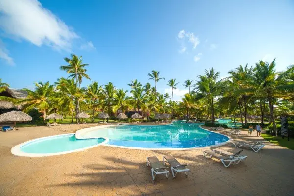 Piscine extérieure de l'hotem Maxi club Punta Cana en République Dominicaine. Belle piscine avec 2 bassin s entourés de cocotiers, palmiers , carbets , transats faisnat face à la mer