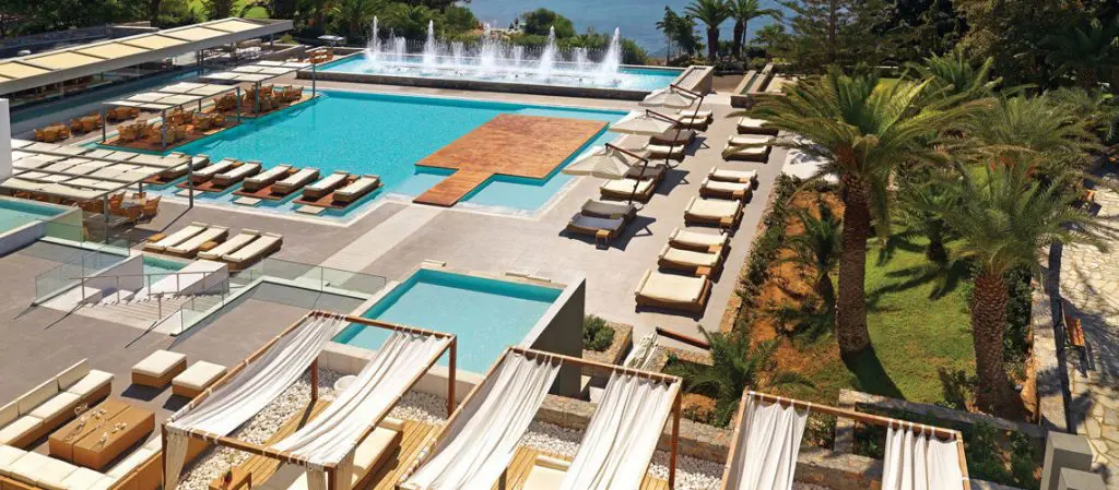 Vue aérienne de la piscine du Club de vacances avec des transats , chaises allongées et des jets d'eaux. Un lieu idéal pour bronzer au soleil pendant son séjour en Grèce. 
