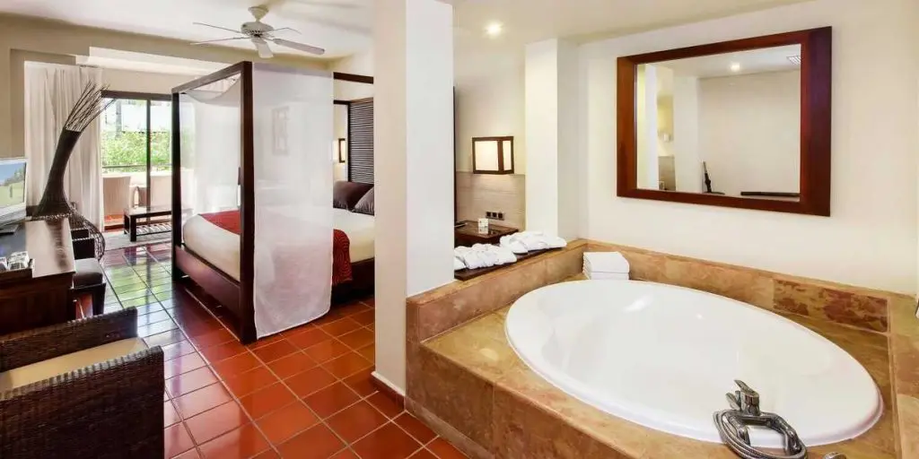 Chambre de luxe avec salle d'eau et grande terrasse avec vue sur le jardin tropical . 