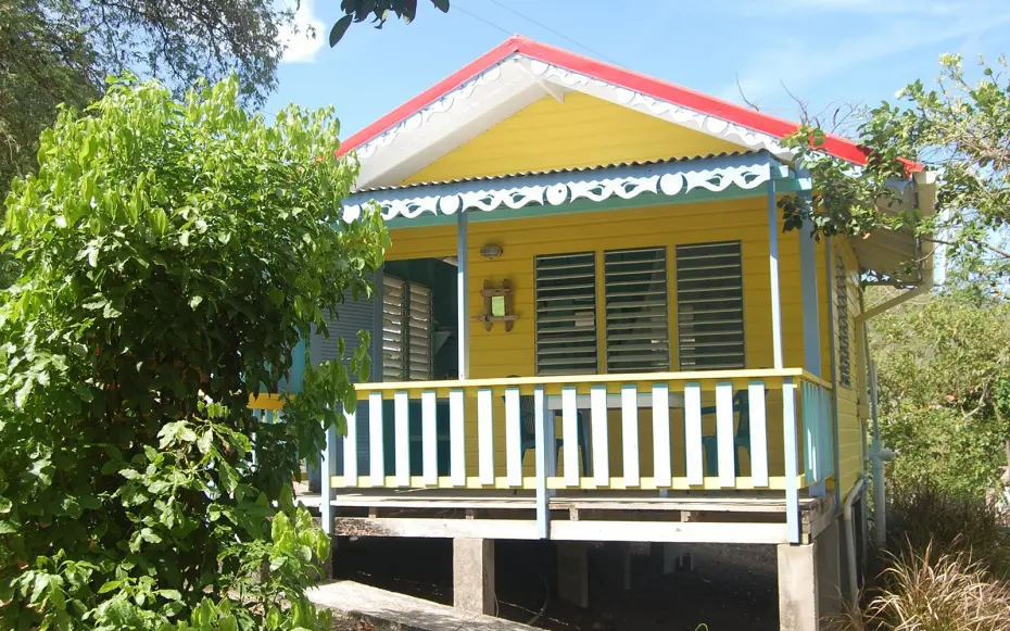 Bungalow en bois jaune avec terrasse .  Situés sur le point panoramique le plus à l'est de Windward Bay, ces cottages élégamment simples sont la porte d'entrée des îles émeraude des Grenadines.