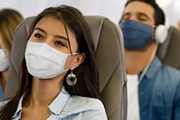 voyageur dans un avion avec le masque : destination pays sans isolement